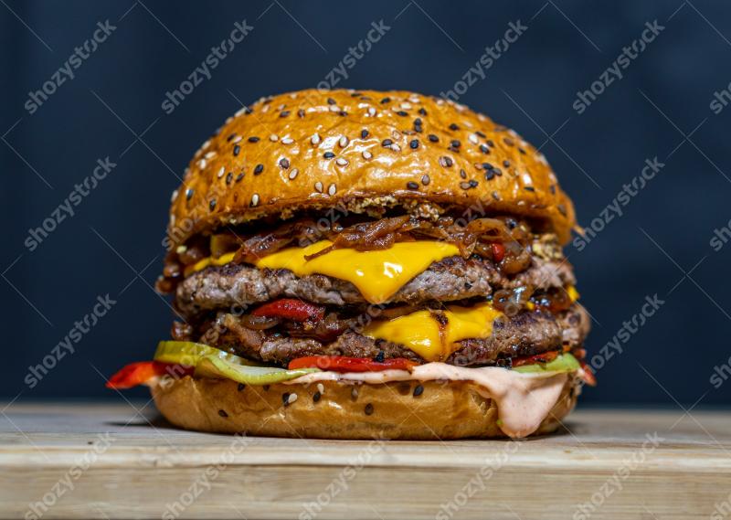 Juicy gourmet burger stacked with melted cheese and fresh toppings on a wooden surface