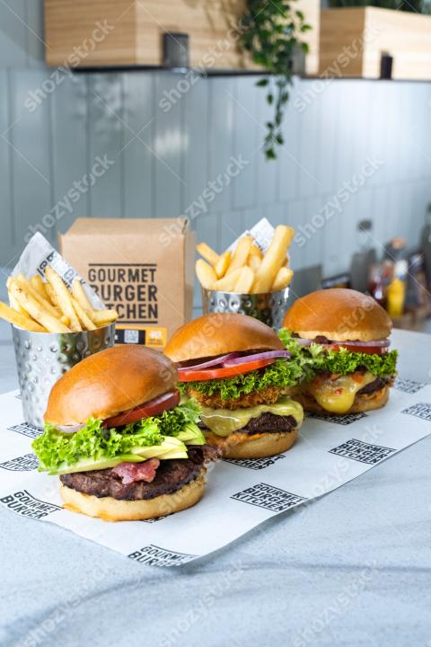 Three delicious gourmet burgers with fries served in a modern kitchen setting